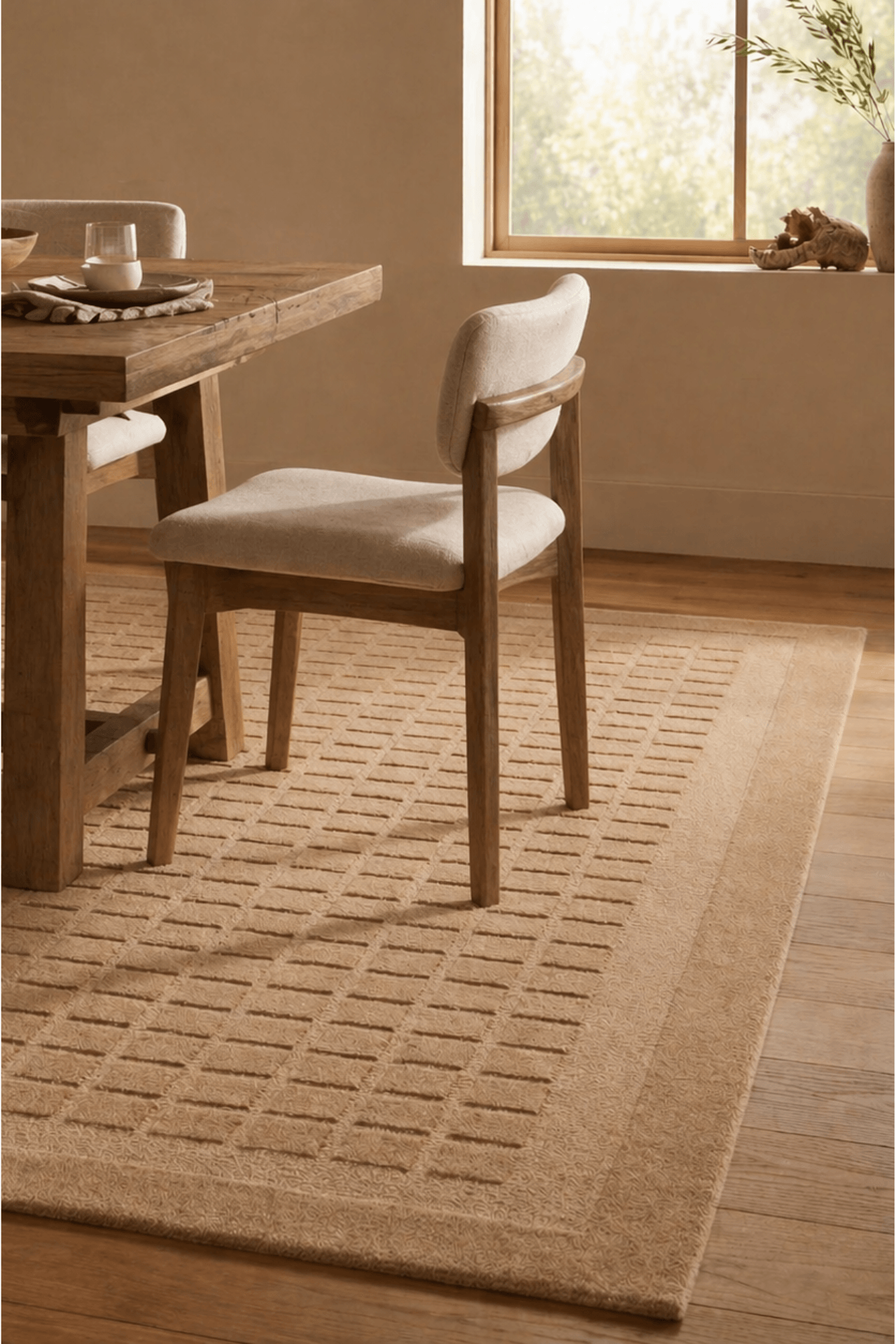 handloom grid rug placed beneath a dining table, enhancing the warmth and elegance of the room.