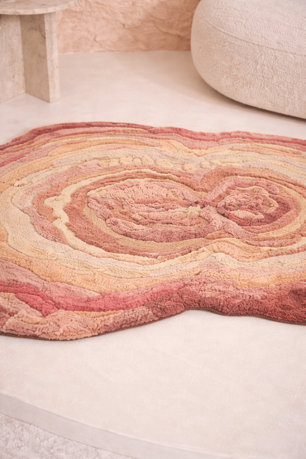 Blush Terrain Organic Rug with layered contours in shades of blush, coral, peach, and beige on a smooth floor surface.