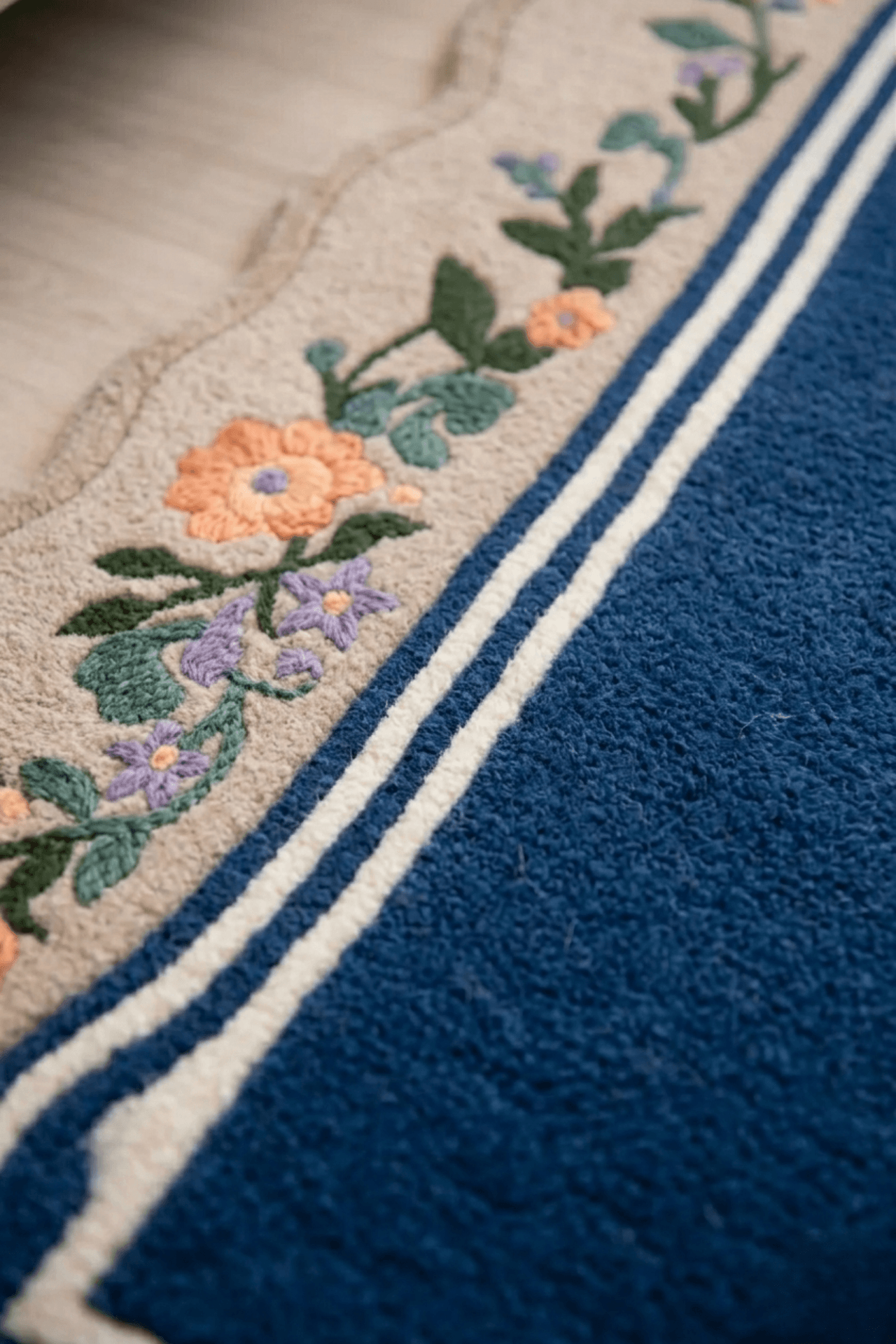 Close-up of the midnight botanical wool rug showcasing scalloped edges and floral design on cream border.