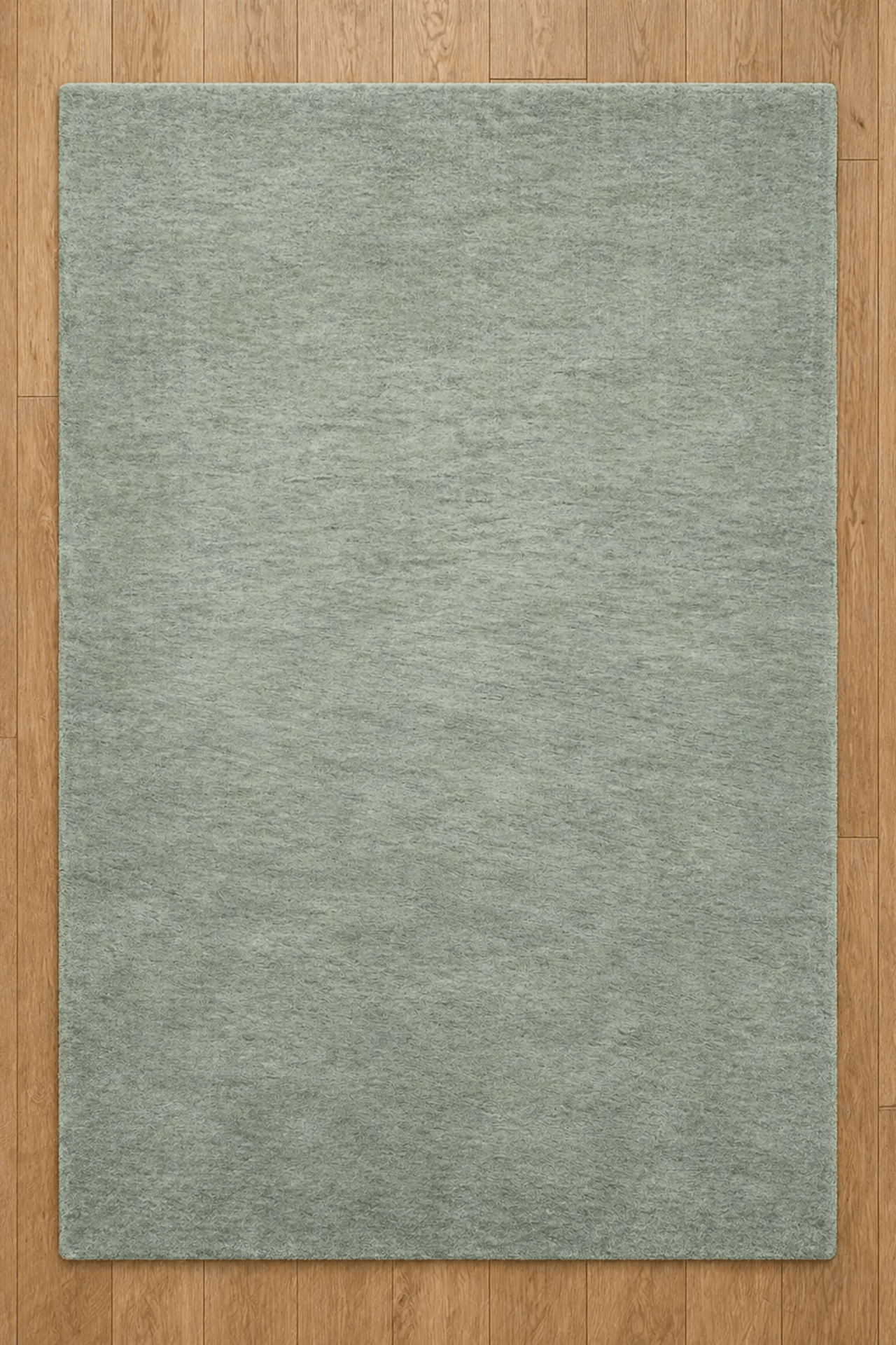 serene sage solid rug on a wooden floor showcasing its soft and plush texture.