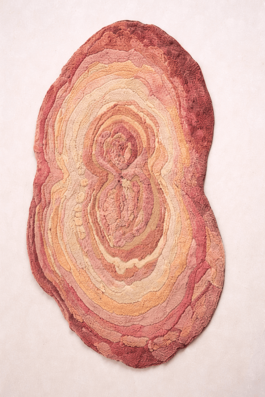 Blush Terrain Organic Rug in a freeform shape with layered contours in shades of blush, coral, peach, and soft beige.
