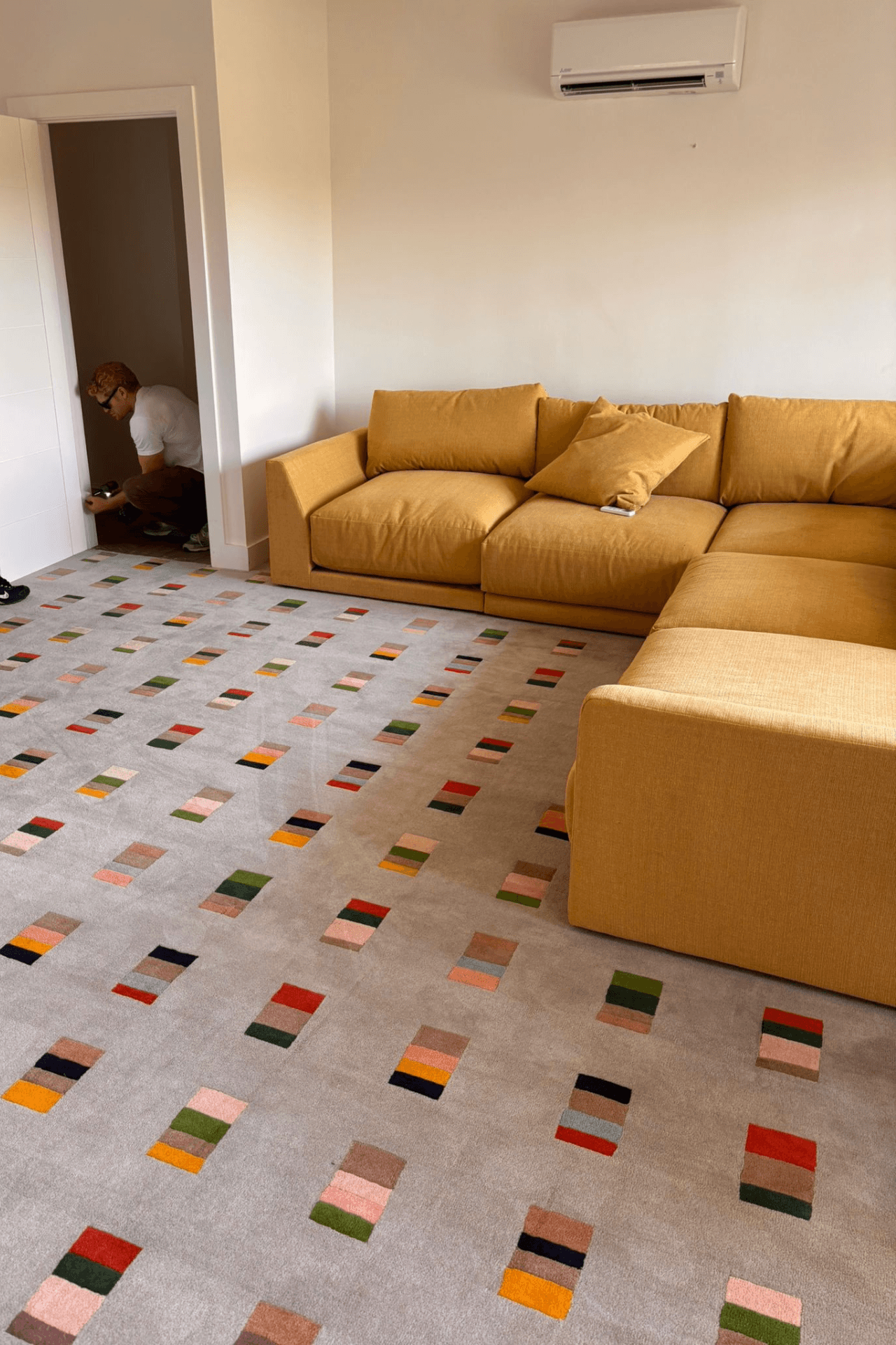 A cozy living room featuring a Mosaic Rhythm Rug, a geometric pattern area rug with multicolor block motifs.