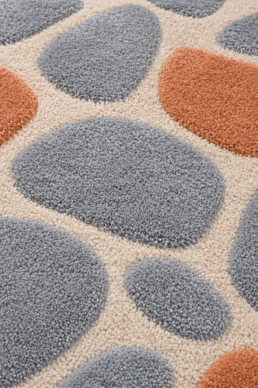 Close-up of the Pebble Harmony hand-tufted wool area rug, featuring abstract, rounded forms in slate blue and terracotta.