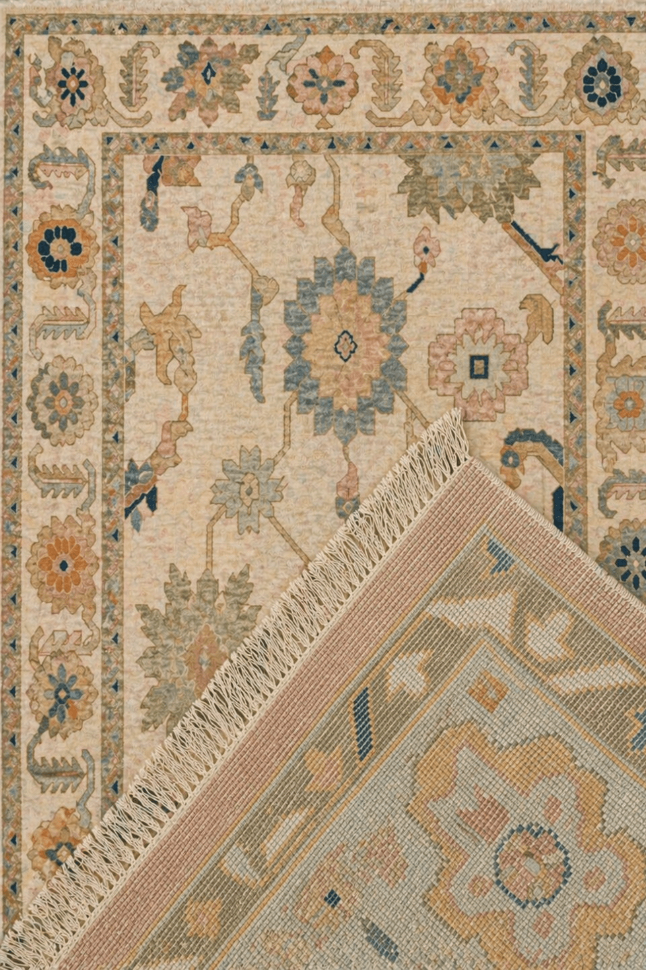 Ivory Bloom Oushak rug with floral medallions in pastel colors and elegant fringed edges.