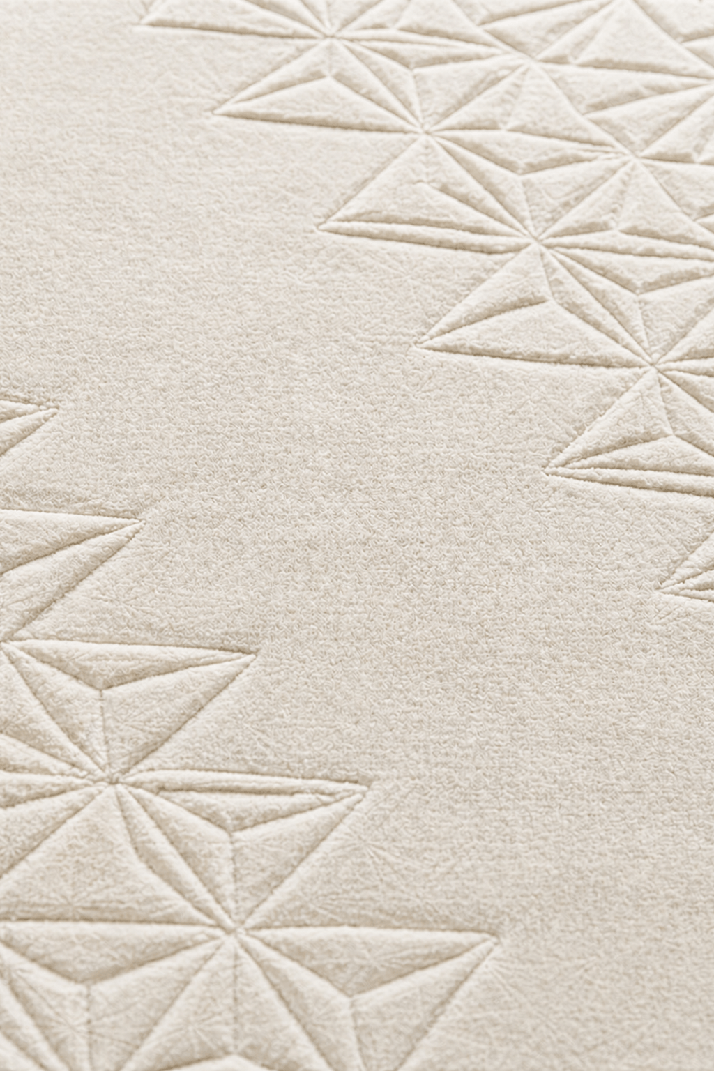 Close-up of ivory geometric wool rug showcasing intricate star-like geometric patterns and textured surface.
