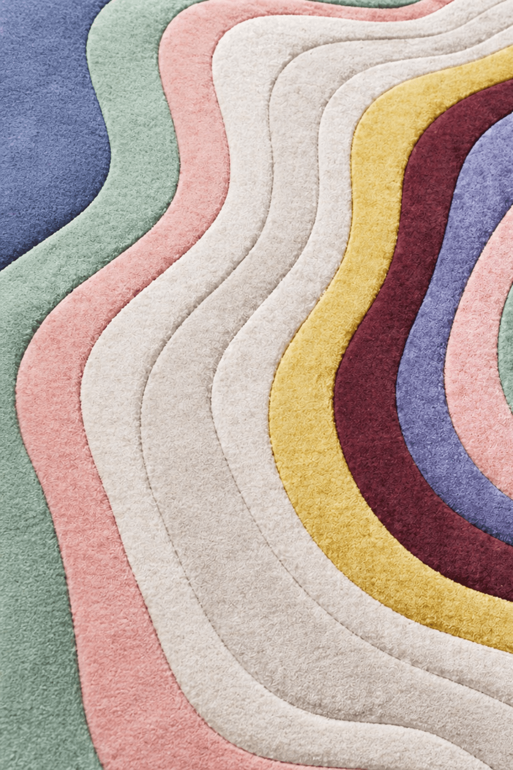 Celestial ripple rug showcasing flowing pastel bands of colors like dusty blue, sage green, blush pink, and warm mustard.