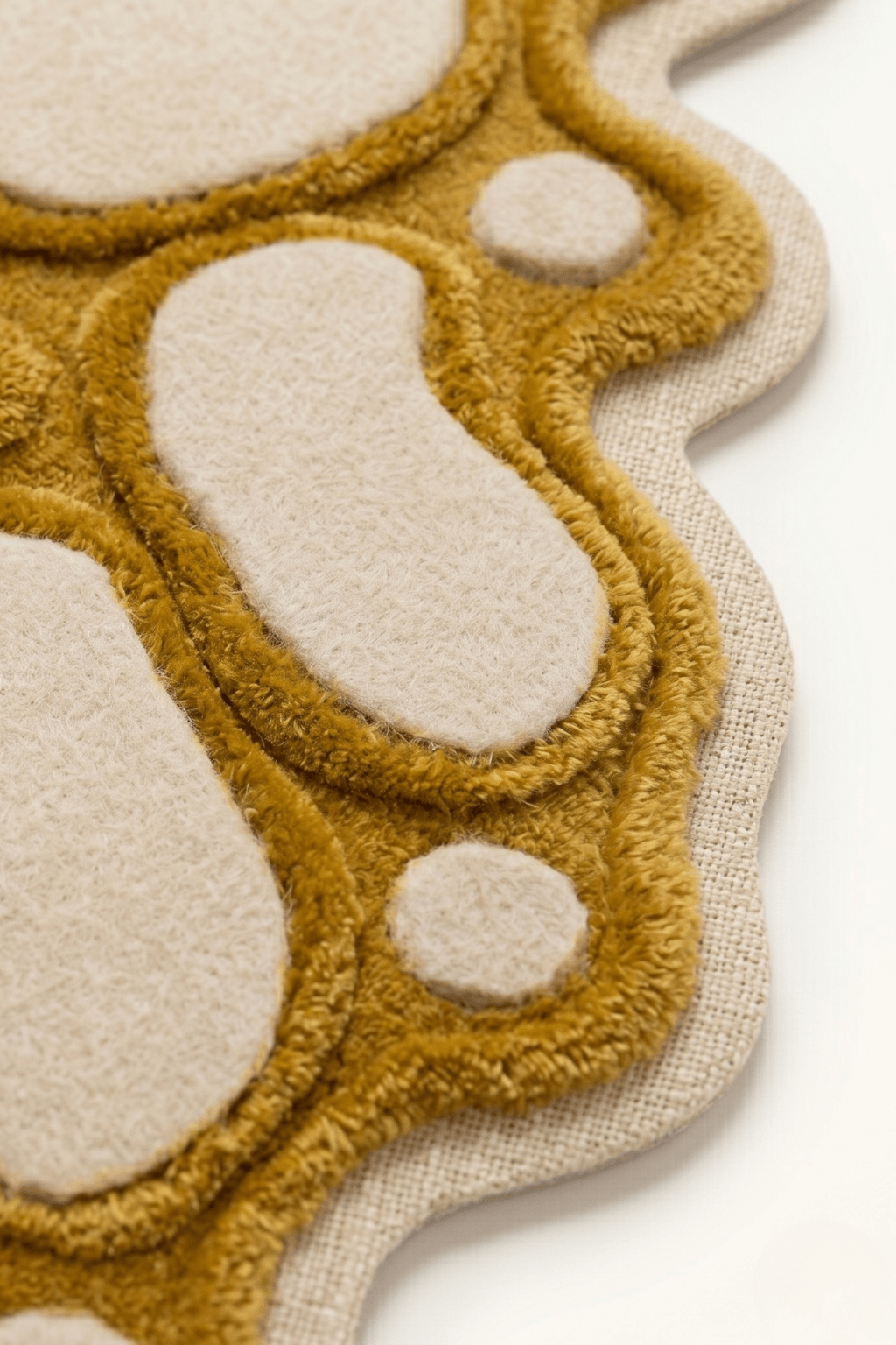 Artistic multi-texture rug featuring a unique design with plush mustard-gold and cream tones.