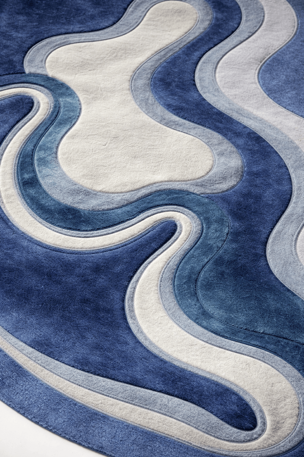 Azure contour rug with organic freeform shape, featuring layered waves of navy, blue, and ivory for a natural look.