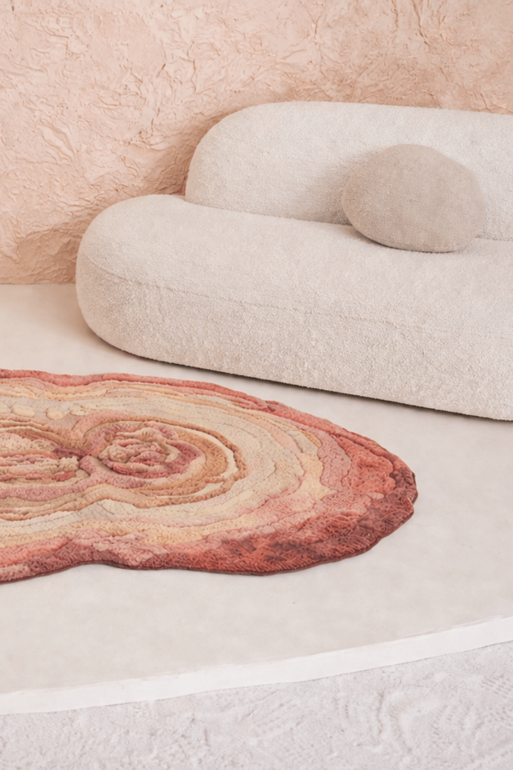 Blush Terrain Organic Rug on a light floor beside a modern beige couch, showcasing its artistic, freeform design.