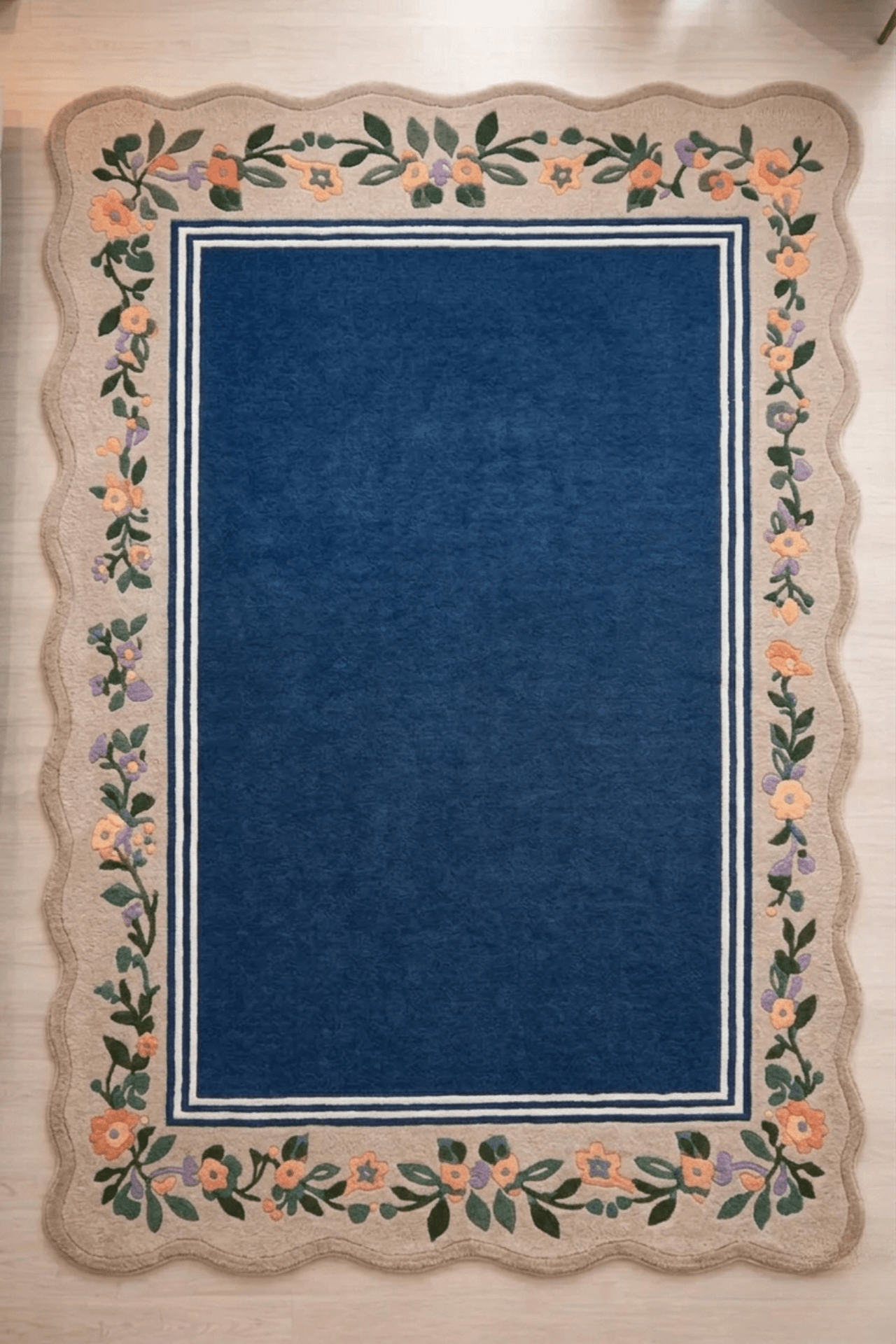 Midnight botanical wool rug featuring a deep blue center and scalloped cream floral border, ideal for enhancing living spaces.