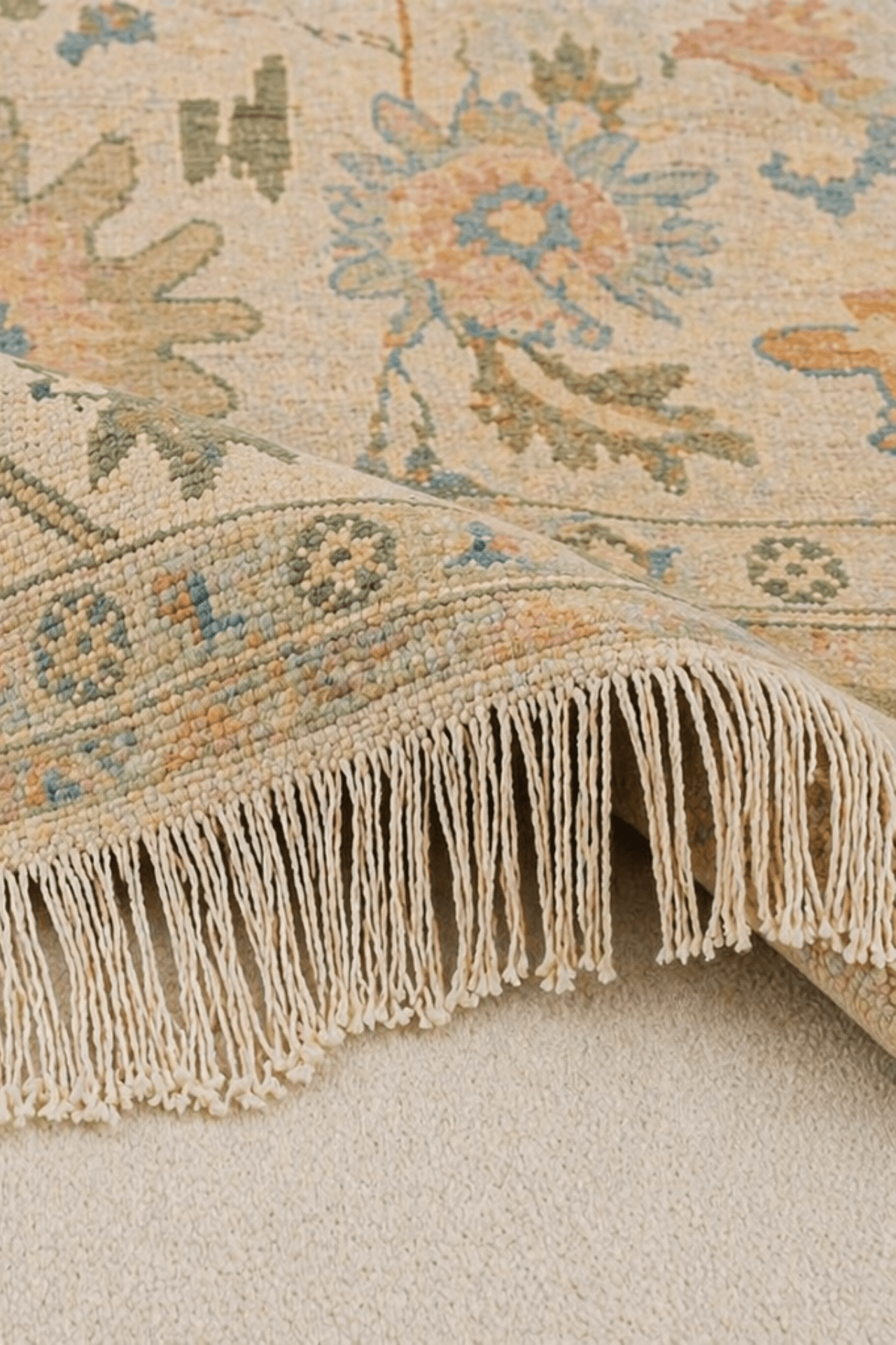 Close-up of the Ivory Bloom Oushak rug showcasing floral medallions and fringed edge.