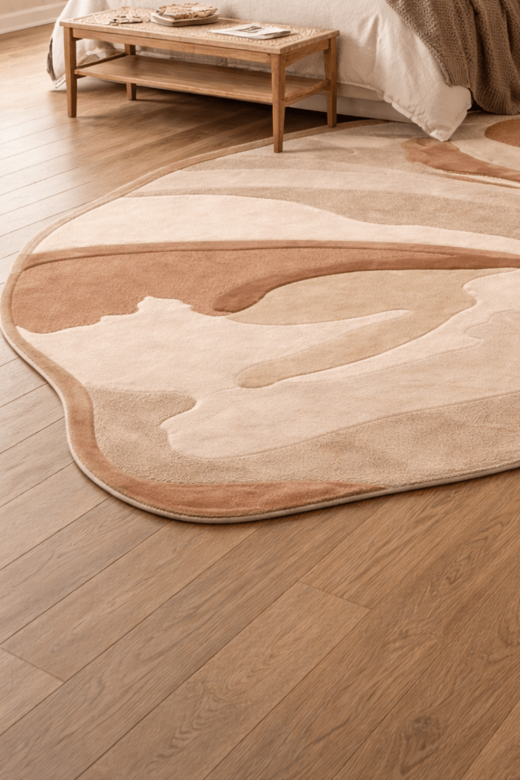 Desert abstract rug on wooden floor, showcasing flowing tones of sand, beige, and terracotta in a stylish interior.