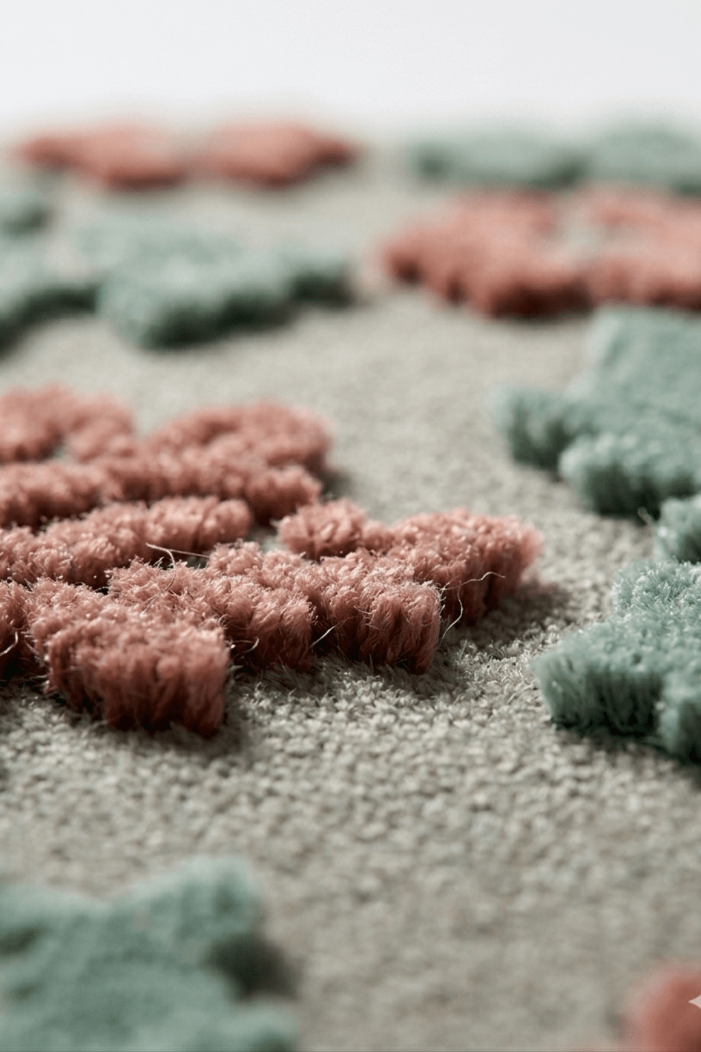 Close-up of the rosewood and sage floral rug showcasing textured floral patterns on a stone-grey background.