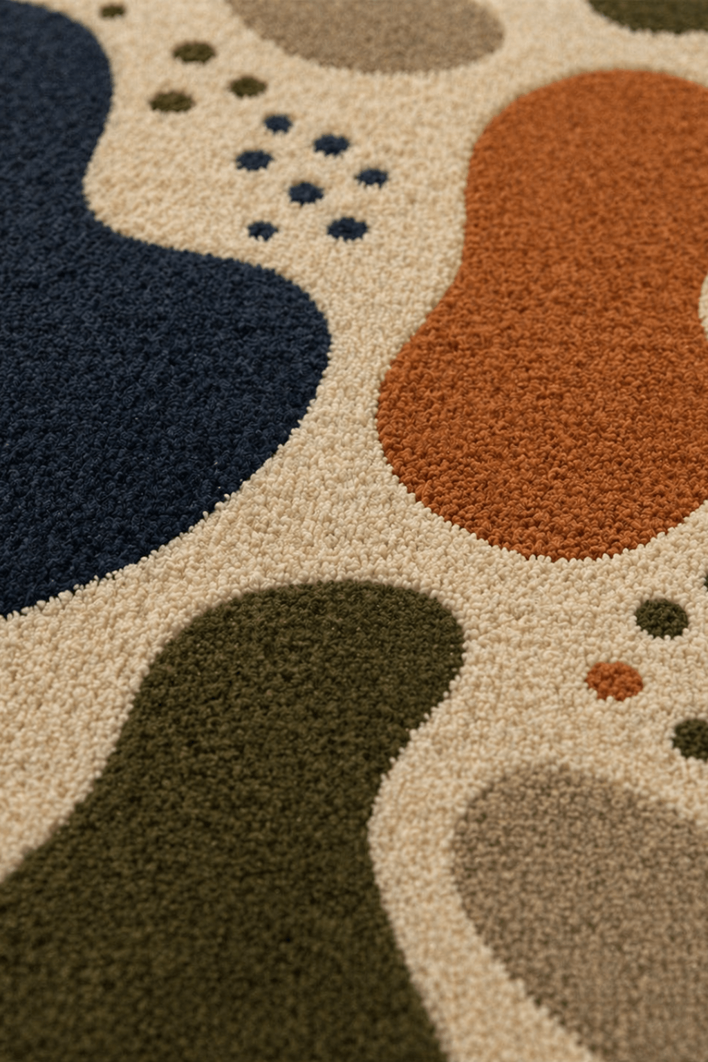 Close-up view of the organic pebble abstract rug showcasing modern shapes in navy, olive green, rust, and beige.