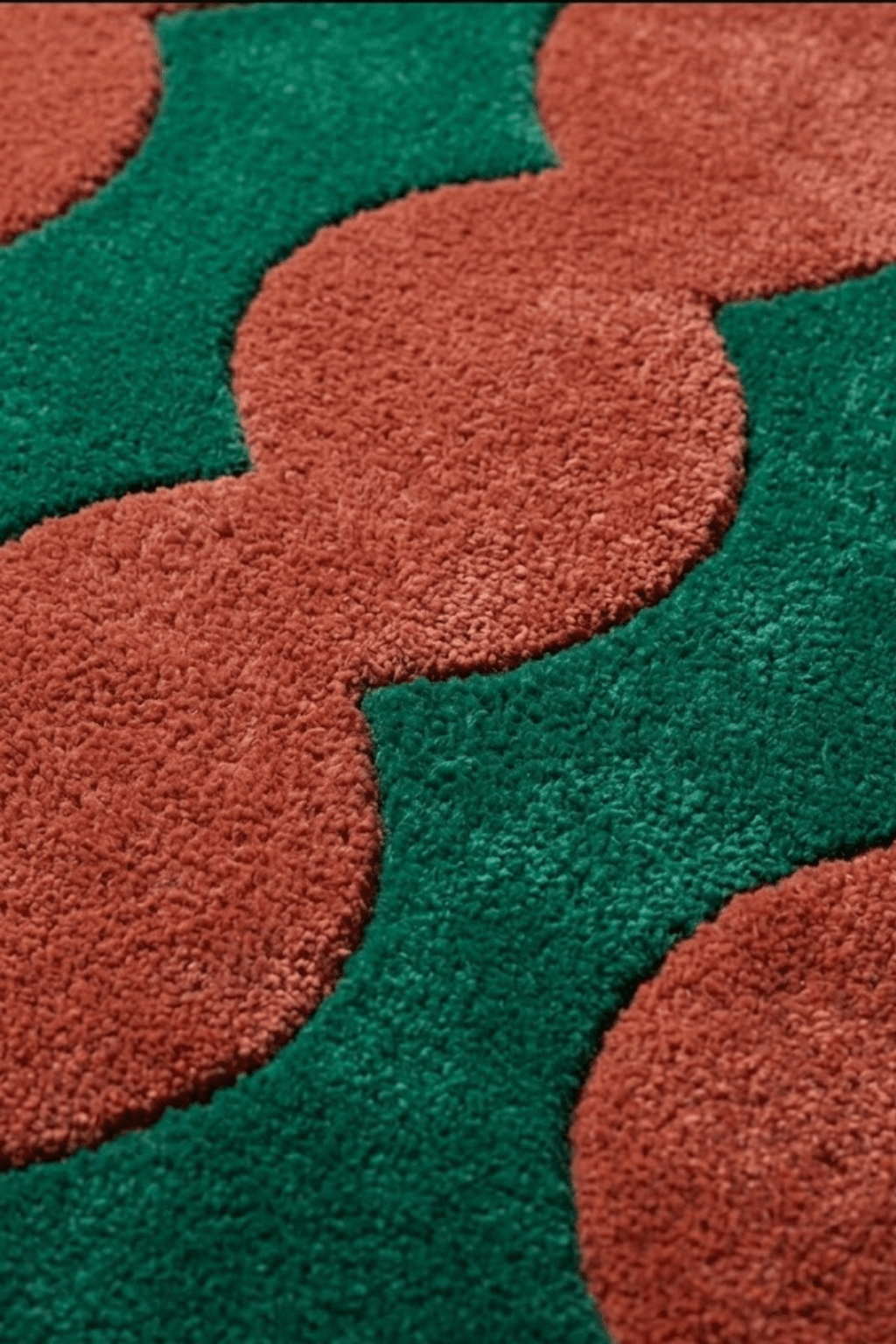 Close-up of Aurora Wave tufted rug featuring bold burnt orange and green undulating pattern.