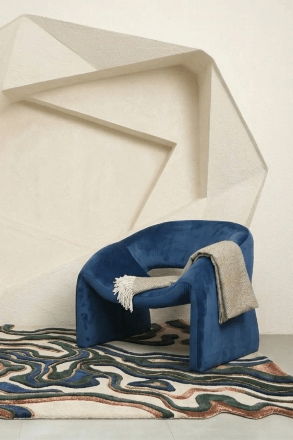 Terra Wave Contour Rug displayed under a blue chair with elegant curves in a modern interior setting.