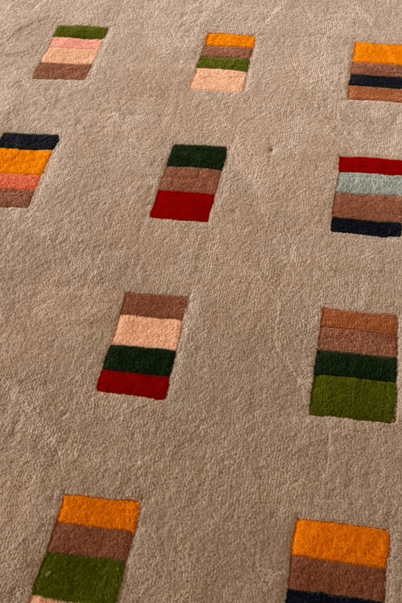 Geometric pattern area rug featuring colorful block motifs on a neutral background, showcasing contemporary design.