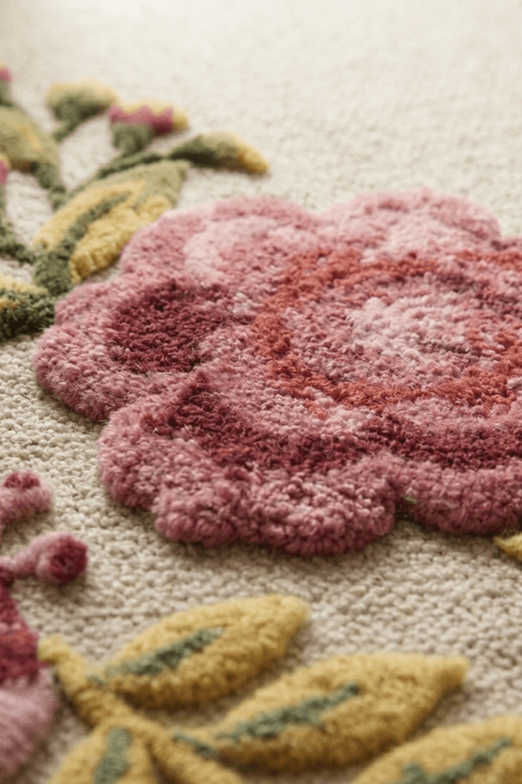 Close-up of a floral hand-tufted rug showcasing intricate pink and green flower details on a textured background.