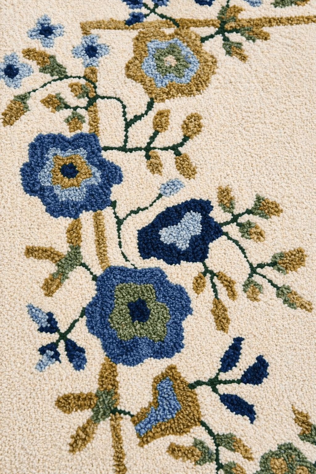 Floral border wool rug featuring intricate hand-tufted floral designs in blue, sage green, and muted gold on a soft ivory base.