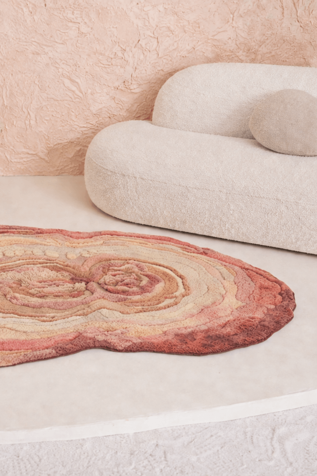 Blush Terrain Organic Rug displayed in a modern living space with a sculptural couch and textured wall.
