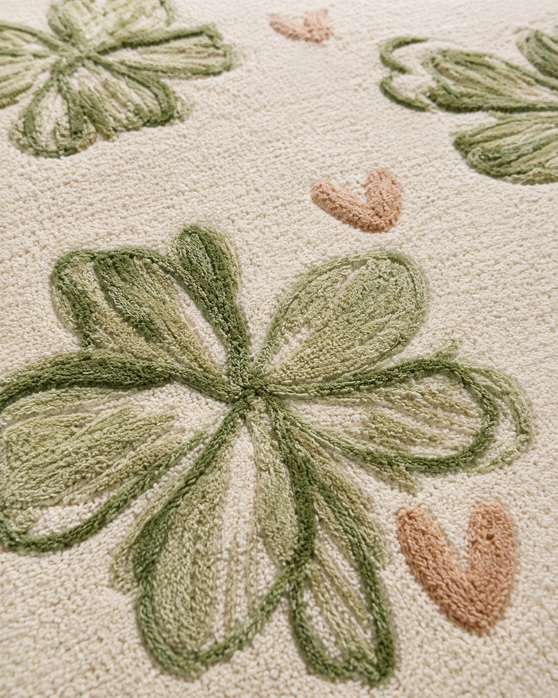 Clover whimsical floral rug with soft sage-green clovers and blush hearts on a warm ivory backdrop.