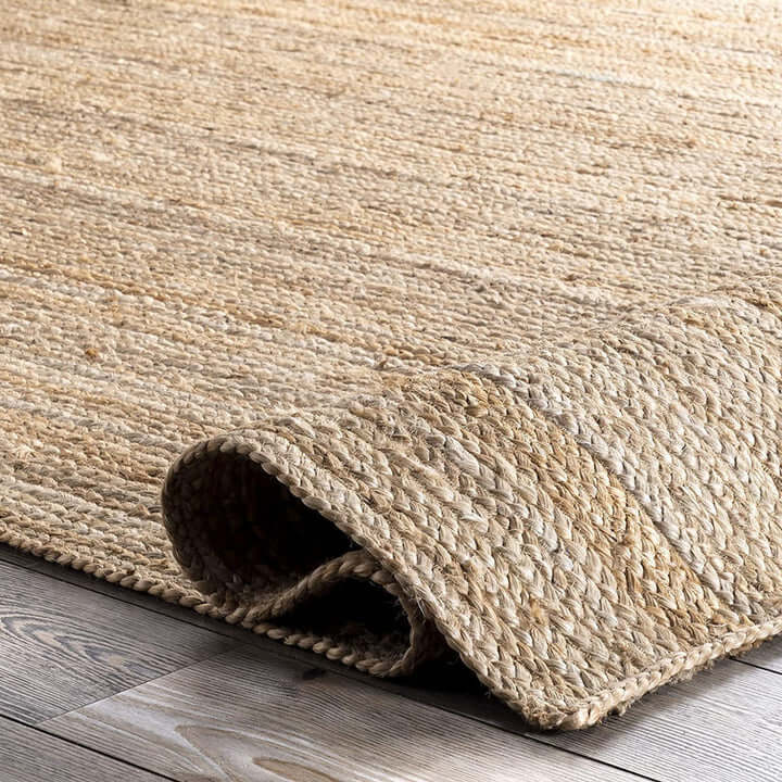 Natural braided jute rug showcasing a braided flatweave design and natural fibers on a wooden floor.