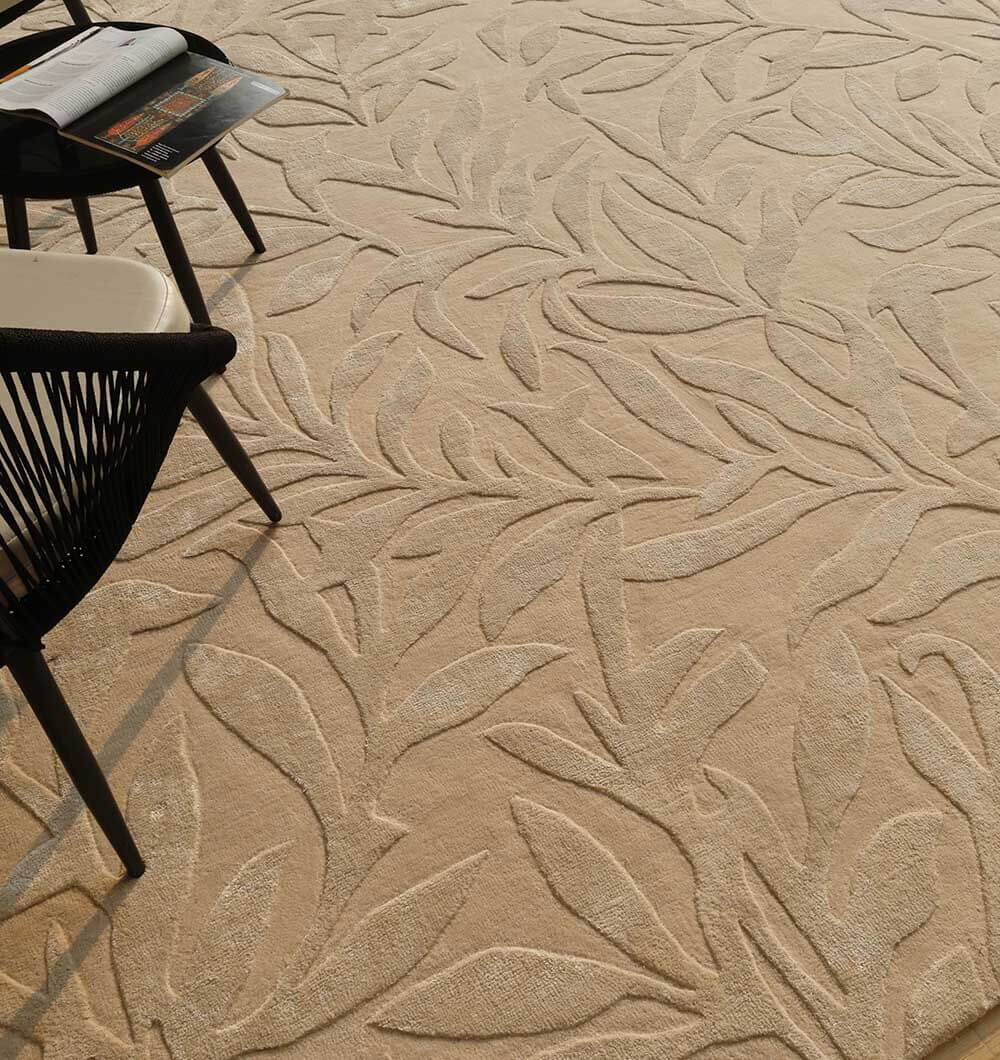 Serenity Leaf Hand-Tufted Rug with intricate leaf pattern in soft neutral tones and modern black chairs.
