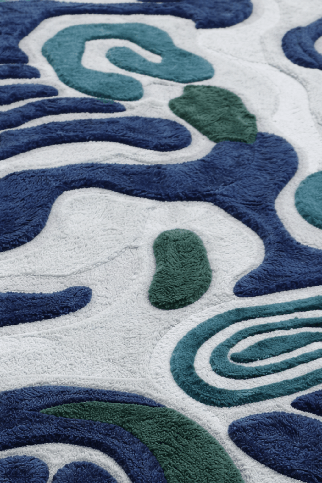 Ocean-inspired hand-tufted rug featuring a captivating pattern in emerald, navy, and seafoam colors.