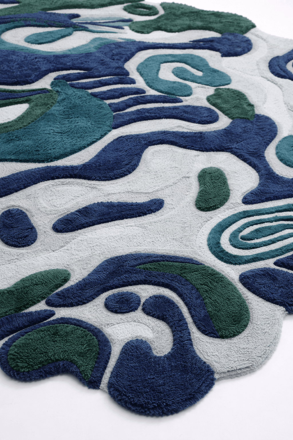Ocean-inspired hand-tufted rug featuring emerald, navy, and seafoam colors with abstract wave patterns.