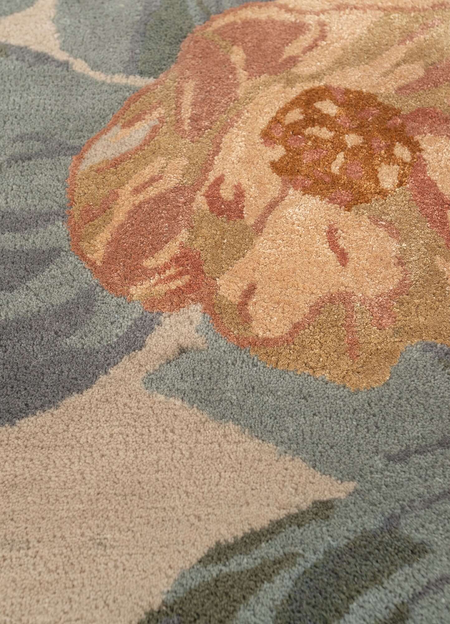 Close-up of a blue haze hand-tufted rug featuring a floral design in soft colors, adding elegance to any space.