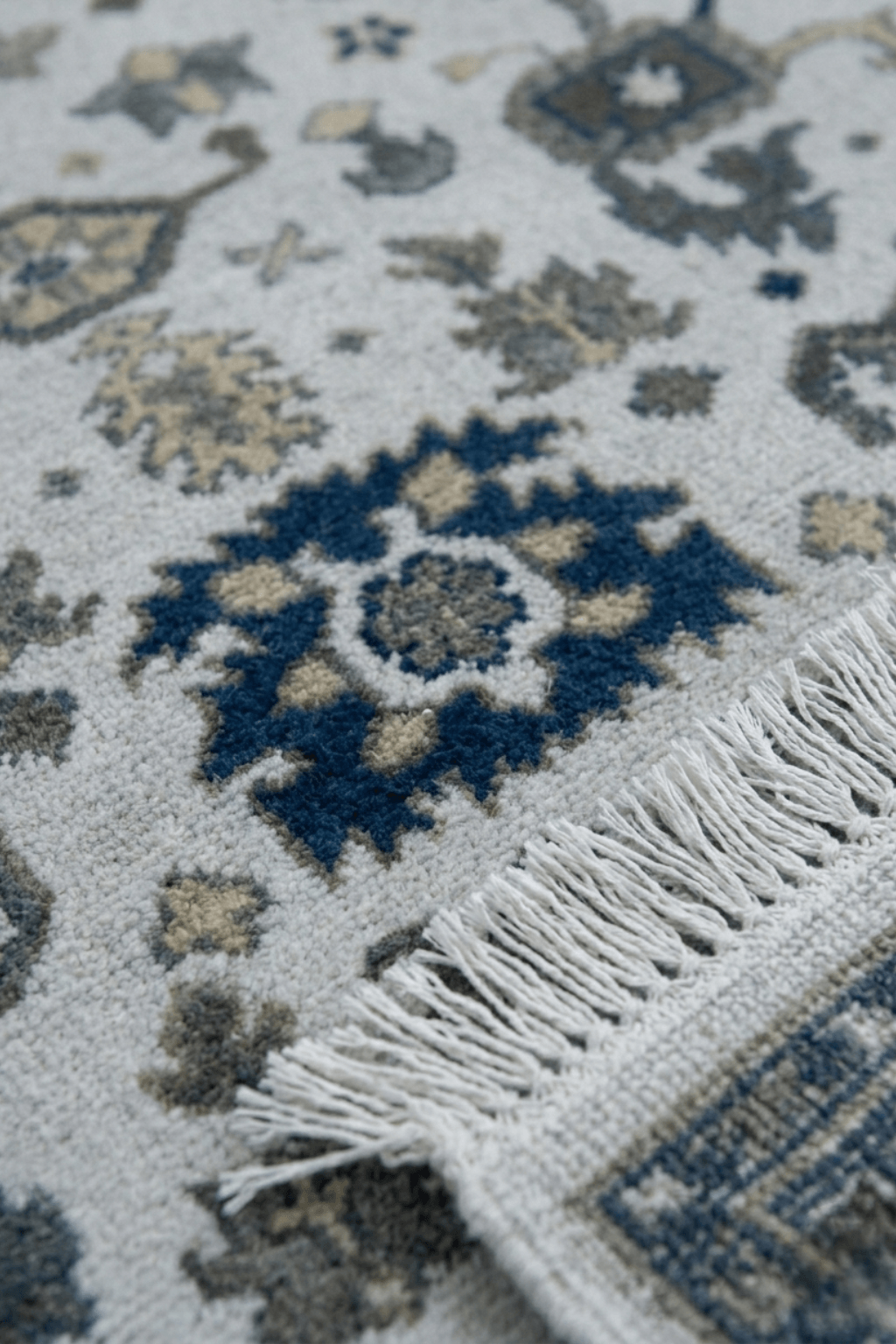 Artisan hand-knotted wool rug with intricate patterns and fringes, showcasing expert craftsmanship and elegant design.