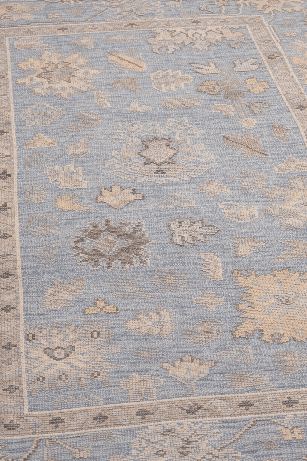 Dusty blue artisan hand-knotted rug featuring intricate floral and geometric motifs.