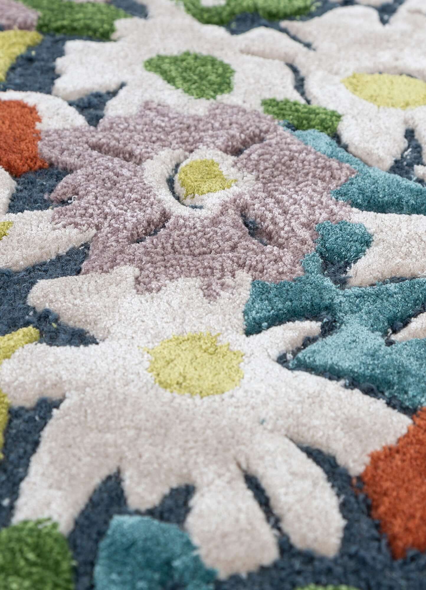 Close-up of an indigo blue and white hand tufted rug with colorful floral design, showcasing soft textures.
